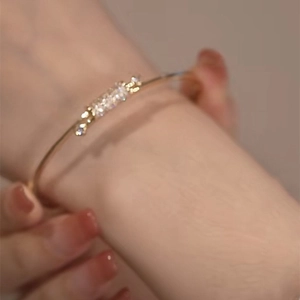 Delicate gold knot bracelet with pavé cubic zirconia worn on a woman's wrist