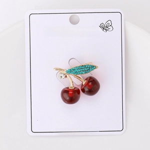 Detailed shot of a gold cherry brooch with red resin fruit and blue rhinestones