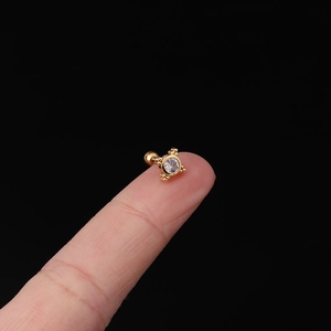 Macro detail of 20G stainless steel helix stud with clear zircon and gold finish