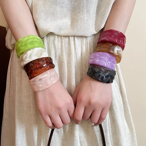 Close-up of stacked acrylic resin bangles with wavy pleated texture in multiple colors