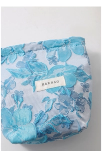 Macro detail of sky blue jacquard fabric showing floral rose patterns and H & R BAG label