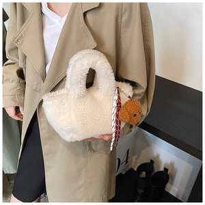 Detail of creamy white plush tote bag texture with cute brown teddy bear keychain