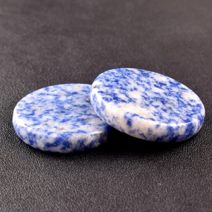 Macro view of blue and white spotted energy crystal stone discs with polished texture