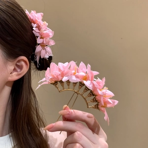 Detailed view of a pink fabric flower hairpin with elegant gold-tone metal base