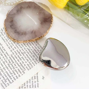 Macro shot of silver mirror heart phone grip on vintage book with jewelry and pearls