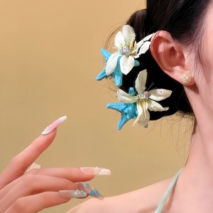 Nahaufnahme von eleganten weißen Stoffblumen- und blauen Seestern-Haarspangen im Haar