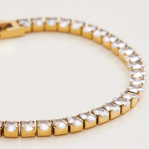 Macro shot of gold-plated tennis bracelet featuring rectangular white zircons and four-prong settings
