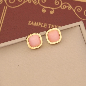 Pink cat eye stone square stud earrings with gold frame on a beige jewelry box