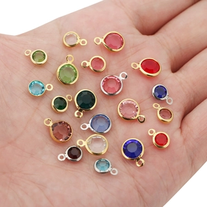 Close-up of colorful 8mm round crystal charms with gold frames held in a hand