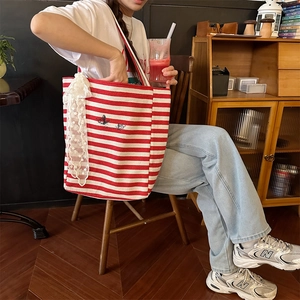 Close-up of red striped canvas bag featuring delicate lace ribbon and floral embroidery