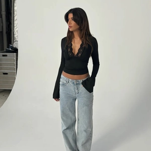 Detailed view of women's black long sleeve top with lace V-neck trim and ribbed texture