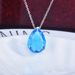 Macro view of pear-cut blue gemstone pendant on a fine silver-tone link chain necklace