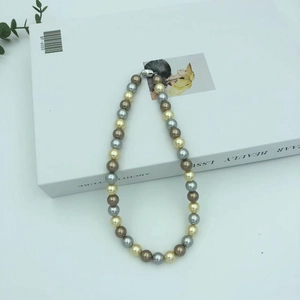 Macro shot of colorful champagne, silver, and chocolate pearl necklace on a white book