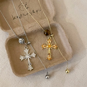 Detail of tiger eye cross pendant necklaces with pavé crystals on textured tray