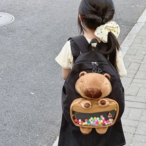 Black kids backpack with plush capybara doll and colorful pom-poms in clear pocket