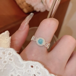 Detailed close-up of a silver ring with light blue gemstone and woven textured band