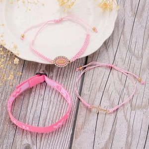 Detail of pink WWJD beaded bracelets with saint medals and cross charms on wooden surface