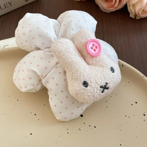 Detail view of a plush polka dot bunny hair tie on a decorative ceramic tray