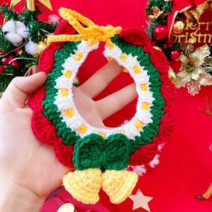 Detail of hand-knitted Christmas pet collar with green crochet pattern and festive bells