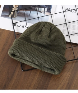 Close-up of olive green chunky knit beanie showing detailed wool texture and stitching