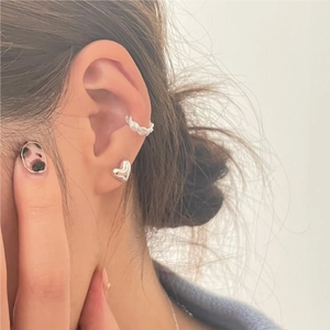 Close-up of a 925 sterling silver heart stud earring and twisted ear cuff on ear