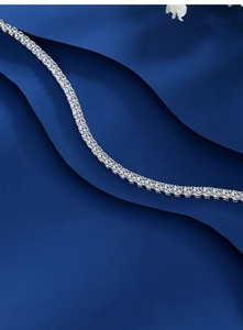 Macro shot of a classic moissanite tennis necklace in silver setting on blue fabric