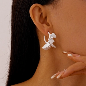 Close-up of elegant white floral earring with a pearl center on a female model