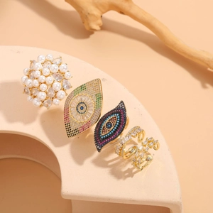Artistic layout of gold devil's eye rings with pearls and zircon on beige props