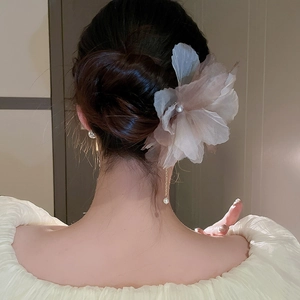 Détail d'épingle à cheveux fleurie en tissu avec perles et pompons dans un chignon élégant