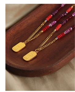 Detail of gold-plated pendant necklace with natural stone beads and lucky engraving