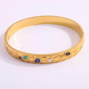 Close-up of golden titanium steel bracelet with evil eye enamel patterns and textured finish