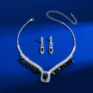 Macro detail of V-shaped silver necklace and earrings with black rectangle gemstones