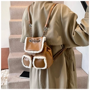 Detail view of brown leather backpack with white plush trim and silver chain straps