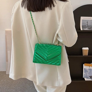 Modern neon green patent leather crossbody bag with V-quilt stitching and gold chain strap