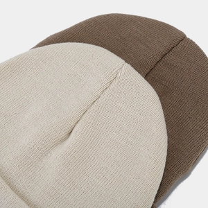 Macro view of beige and coffee brown knit beanie showing tight texture and top stitching