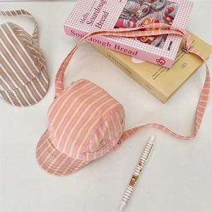 Detail of creative hat-shaped crossbody bag with pink and yellow stripes and strap