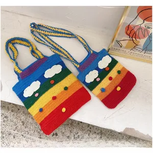 Detail of handmade rainbow knit bag featuring 3D cloud and pom-poms in two sizes