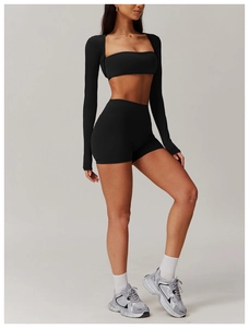 Detail of high-waist black gym shorts and shrug top on a model with grey background