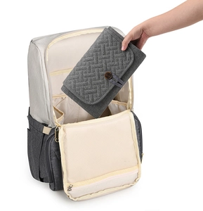 Detail of folding gray quilted diaper mat into beige travel backpack compartment