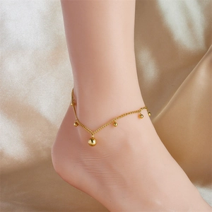 Detail of gold-plated stainless steel anklet with metal beads on champagne silk