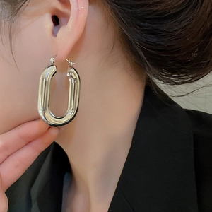 Primo piano di un orecchino a cerchio ovale in argento indossato da una modella