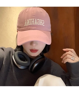 Close-up of pink baseball cap featuring detailed white letter embroidery on twill fabric