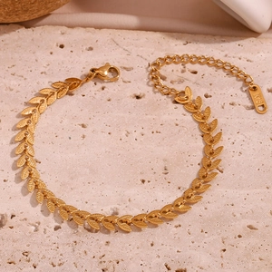 Macro shot of gold leaf chain bracelet with 18K hallmark on textured stone