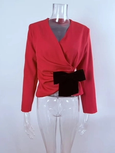 Detail view of red wrap top with V-neckline and large black bow accent on the waist