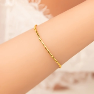 Close-up of 18K gold-plated box chain bracelet worn on wrist showing fine metal texture