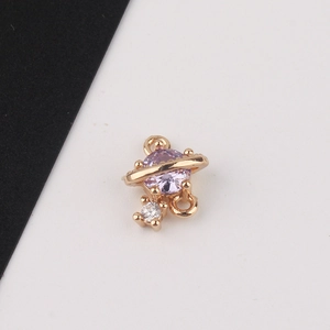 Macro detail of gold-plated planet charm with purple and white zircon for DIY jewelry