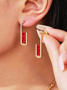 Macro detail of luxury geometric earrings with rectangular red zircons in gold setting