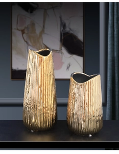 Detailed view of two gold ceramic vases with vertical texture and wavy rims for home decor