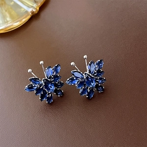 Macro shot of butterfly stud earrings featuring blue marquise-cut zircons on leather