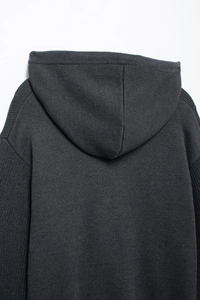 Close-up of dark grey knitted hoodie showing fabric texture and shoulder detail